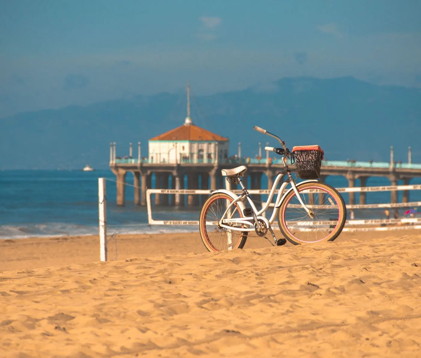 A beach cruiser on the sand with the Manhattan Beach Pier behind it